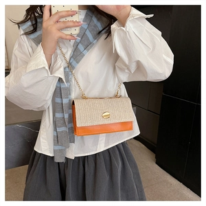 Détail du sac bandoulière en paille tissée et cuir orange avec chaîne dorée et fermoir