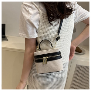 Fashionable contrast canvas and black leather crossbody bag worn by a model in a modern interior