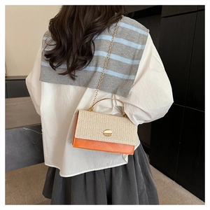 Detail of woven straw and orange leather crossbody bag with golden metal handle