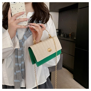 Détail du rabat en paille tissée et base verte d'un sac chic avec poignée dorée