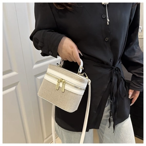 Detail of cream woven texture mini bag with white trim and dual gold zippers