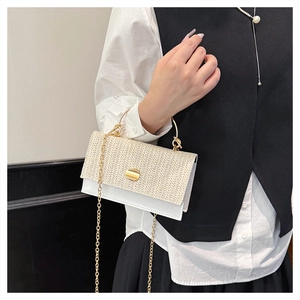 Detail of woven beige handbag with gold metal handle and chain strap on a model