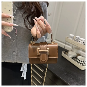 Détail d'un mini sac bandoulière marron vintage avec boucle carrée dorée et bandoulière chaîne