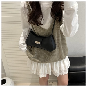 Model wearing a black matte leather baguette bag with a rectangular gold metal buckle