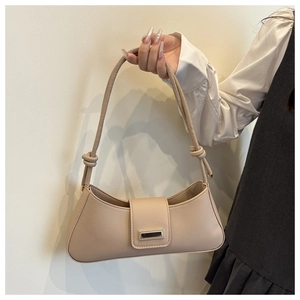 Detail of beige faux leather baguette bag with golden buckle and stylish knot strap