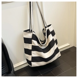 Detail view of large striped canvas tote bag hanging on a white wall in a modern room