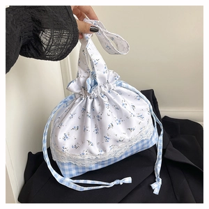 Close-up of drawstring bag with blue floral patterns, lace trim and gingham textures