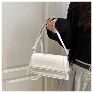 Close-up of a white leather flap square bag with light gold hardware and smooth finish