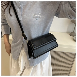 Detail of a minimalist black square crossbody bag with adjustable leather shoulder strap
