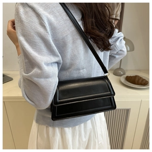Minimalist black leather flap underarm bag shown on model for size and style reference