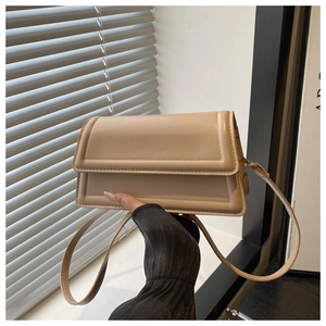 Detail of cream flap crossbody bag with raised edge stitching and slim shoulder strap