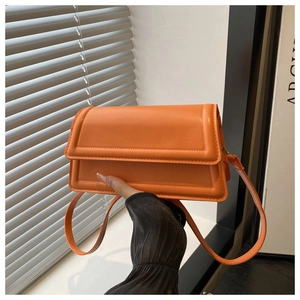 Close-up of bright orange matte leather crossbody bag with detailed stitching on flap