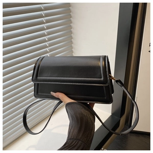 Detail shot of a black leather rectangular shoulder bag with double topstitching and flap