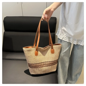 Detail of straw woven tote bag featuring brown lace embroidery and leather handles