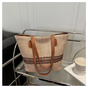 Close-up of woven straw tote bag featuring brown lace trim and leather shoulder straps