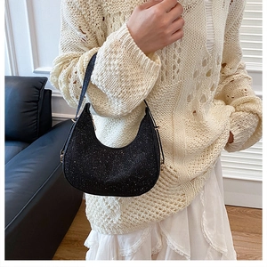 Detail of black sequined crescent hobo bag with shimmering texture and gold hardware