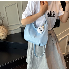 Detail der hellblauen Hobo-Tasche aus Lackleder mit weißem Plüsch-Monster-Anhänger