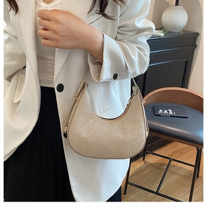 Detail shot of golden sequin hobo bag on a model wearing white suit in modern room