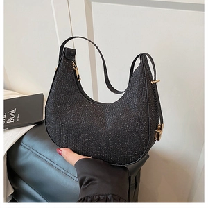 Close-up of black sequin crescent shoulder bag showing shiny texture and zipper detail