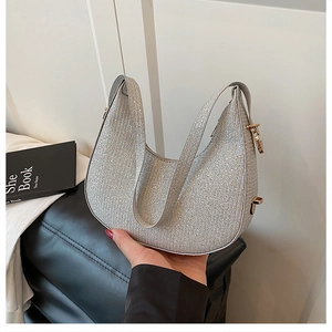 Detail of silver glitter crescent bag with golden metal hardware and shoulder strap