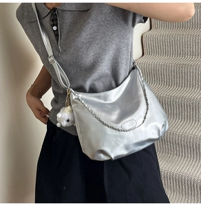Details der silbernen Hobo-Tasche mit Kette und süßem weißem Schaf-Plüschanhänger