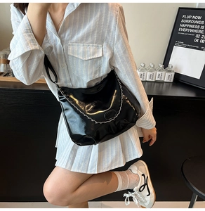 Minimalist black glossy leather crossbody bag with silver chain detail on model