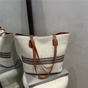 Chic woven tote bag with brown leather handles and decorative lace stripes for summer fashion
