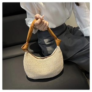 Detail of hand-woven straw shoulder bag with leather handle and smooth zipper closure