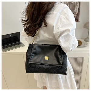 Détail du sac bandoulière noir en similicuir avec texture serpent et chaîne dorée