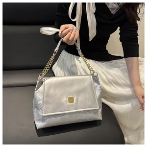 Détail du sac à main argenté avec texture serpent et fermoir à boucle métallique carrée dorée