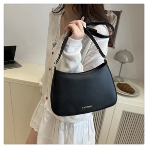 Détail d'un sac d'épaule demi-lune noir minimaliste avec lettrage FASHION doré imprimé