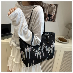 Detail of black tote bag featuring colorful wave embroidery and slim shoulder straps