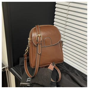 Close-up of brown leather crossbody bag featuring contrast stitching and gold metal hardware