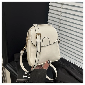 Detail of a beige leather crossbody bag featuring dual zippers and adjustable golden buckle