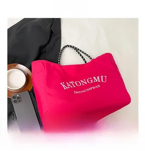 Detail of rose pink tote bag with white lettering and black white checkered handles