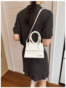 Détail du mini sac blanc en cuir PU avec logo doré et poignée circulaire élégante