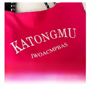 Detail of fuchsia canvas tote with KATONGMU lettering and black woven handle strap