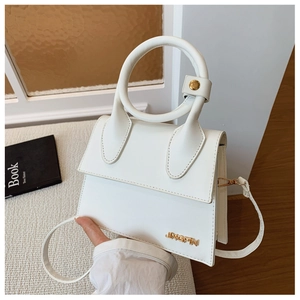 Détail du sac à main en cuir blanc avec poignée ronde, bijoux dorés et logo métal