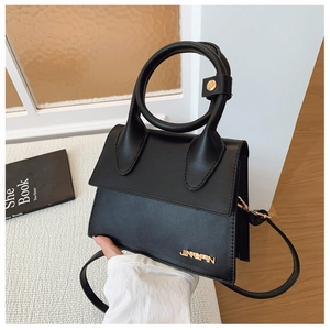 Gros plan détaillé d'un sac à main noir en similicuir avec poignée ronde et logo doré