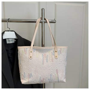 Detail of light beige tote bag with colorful wavy embroidery and embossed texture