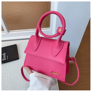 Détail du sac à main rose avec poignée ronde et logo doré en scène de la vie