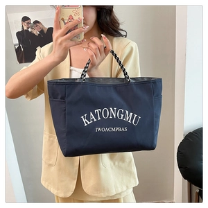 Detail of navy blue tote bag with white lettering and woven handle in mirror selfie