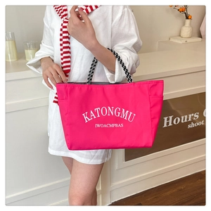 Detail of hot pink nylon tote bag featuring black and white checkered woven handles