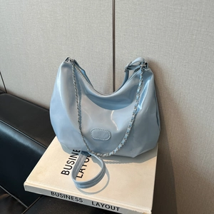 Détail d'un sac hobo bleu clair avec bandoulière chaîne argentée et cuir brillant lisse
