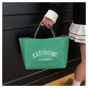 Detail of green nylon tote bag with large letter print and woven rope handles