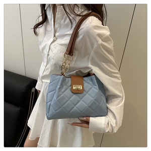 Detalle del bolso tote acolchado azul claro con correa de cuero marrón y cadena dorada