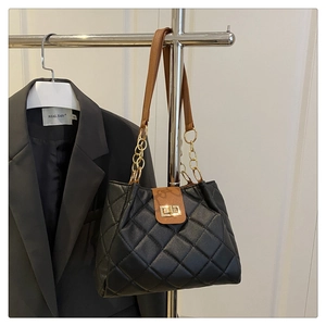 Detalle del bolso de hombro de cuero negro acolchado con cadena de oro y cierre giratorio