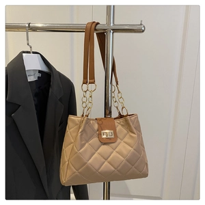 Detalle del bolso tote acolchado con cierre dorado y correa de cadena en color marrón