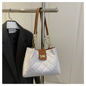 Detalle de bolso acolchado blanco con correa de cadena de metal y cierre giratorio