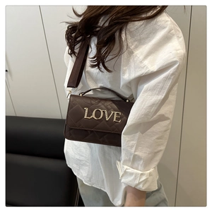 Detail of a brown quilted shoulder bag featuring gold LOVE lettering and elegant stitching